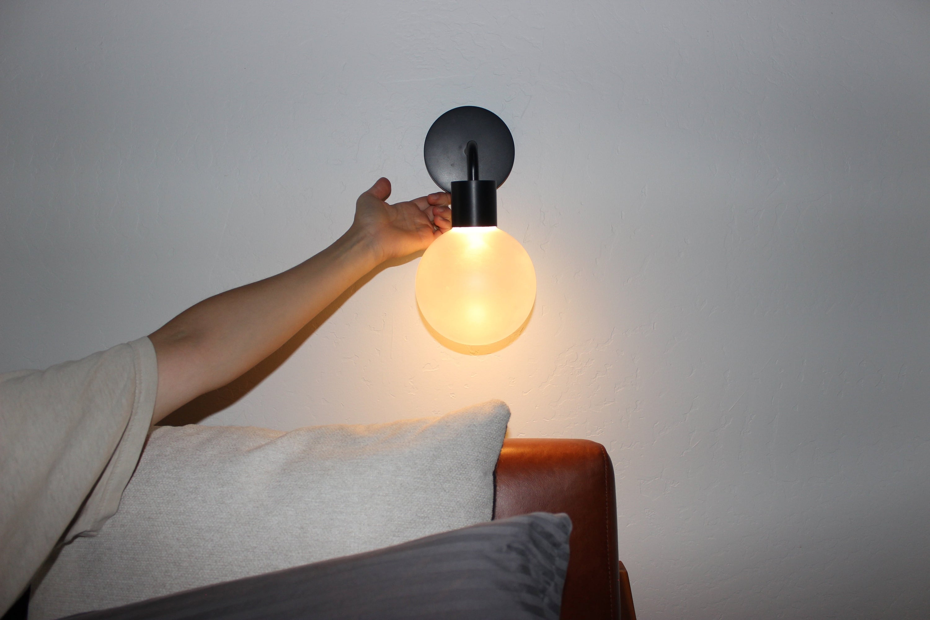 A hand adjusting the light temperature of a rechargeable wall light sconce.