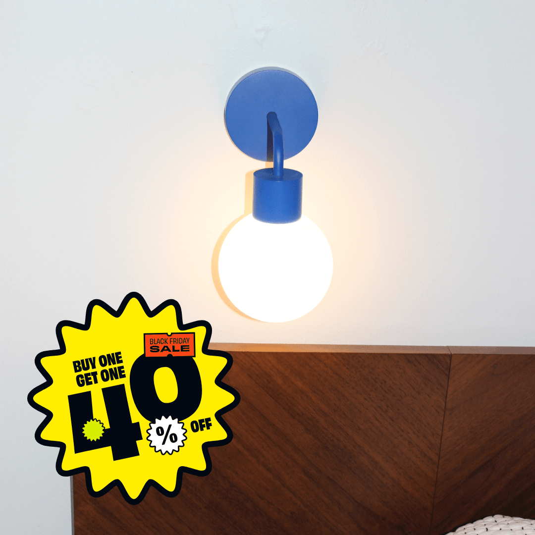 Blue Poplight rechargeable sconce mounted on a beige wall above a wooden headboard with a yellow and black starburst promotional badge reading &