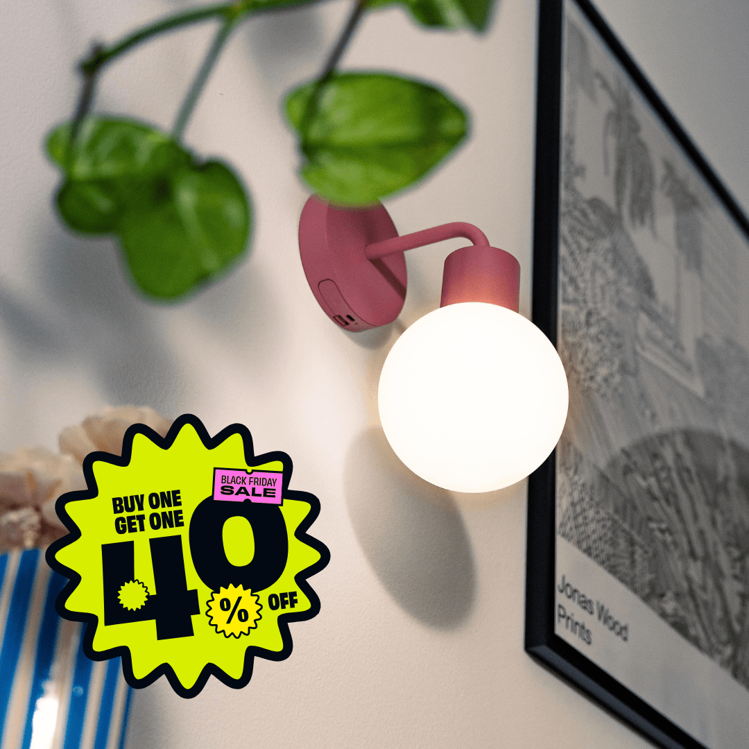 Dusty Rose Poplight rechargeable sconce positioned beside a black and white frame with promotional badge &