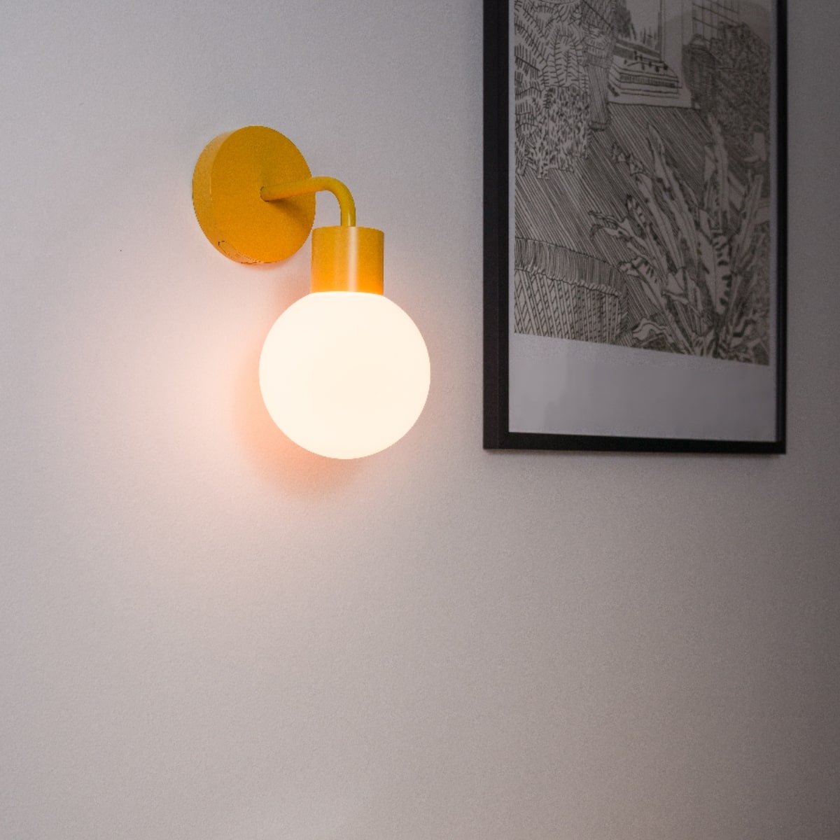 PL Marigold rechargeable wall light sconce illuminates a white wall next to a framed black and white artwork
