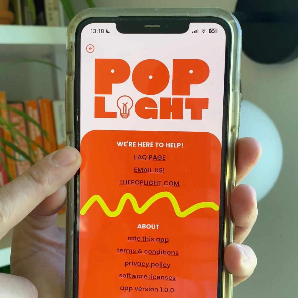 Person holding a phone displaying the Pop Light app interface with help information and colorful design.