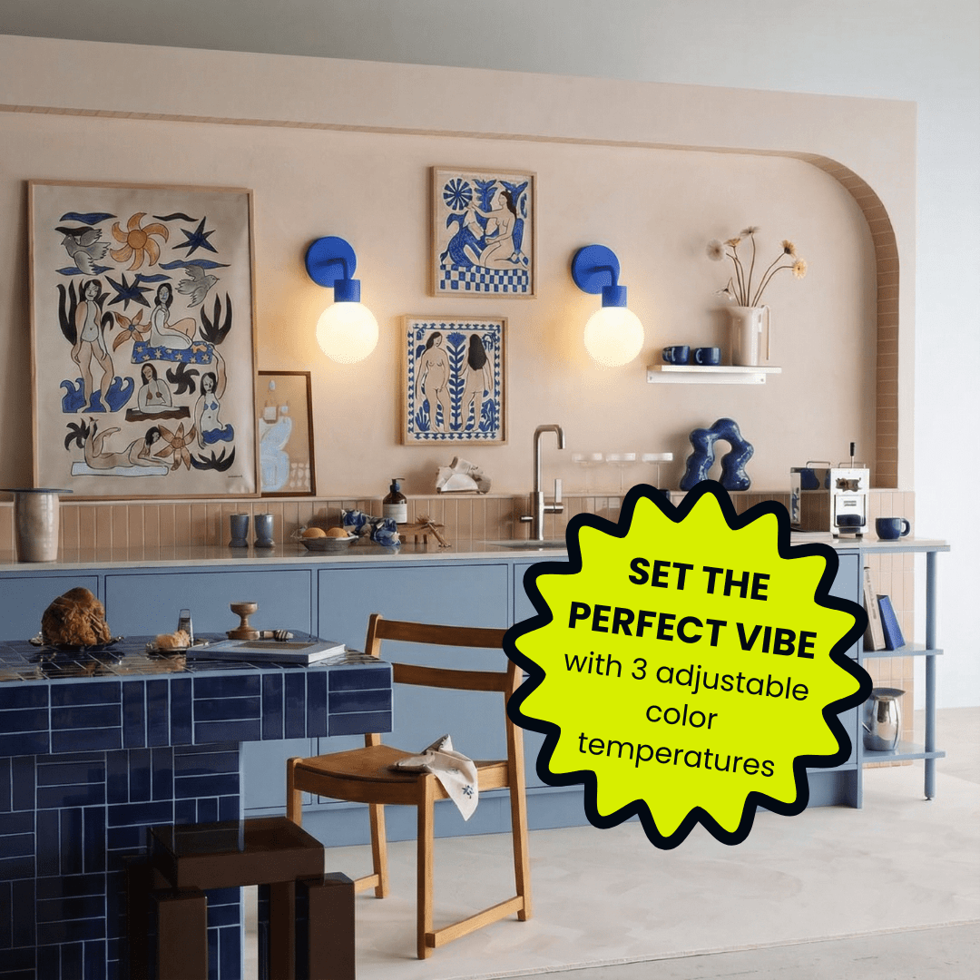 Modern kitchen with blue tile island, beige walls, blue and white figurative art prints, with Poplight Blue wall sconces, and wooden chair