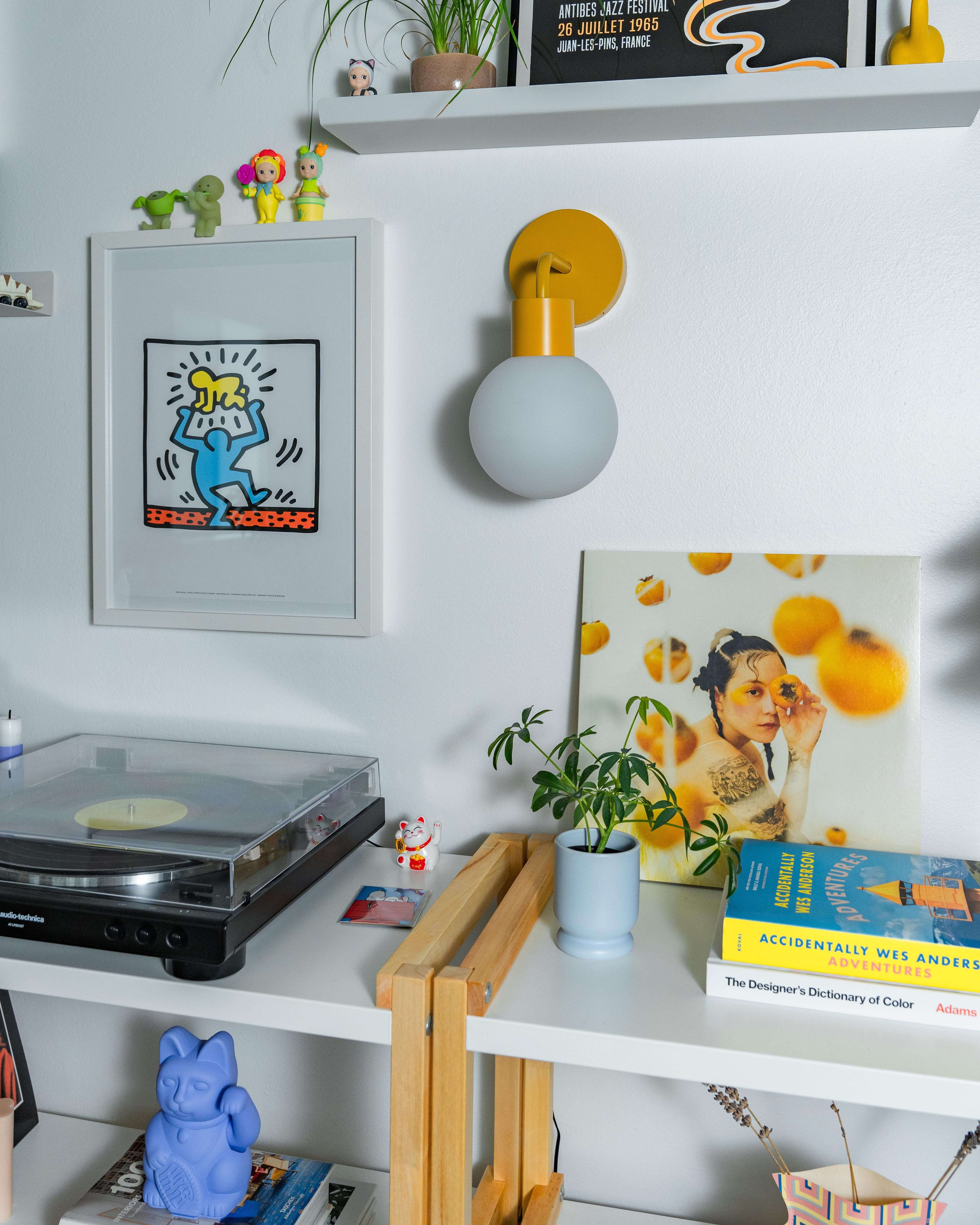 Renter-friendly rechargeable wall sconce illuminating a stylish shelf with decor and books.