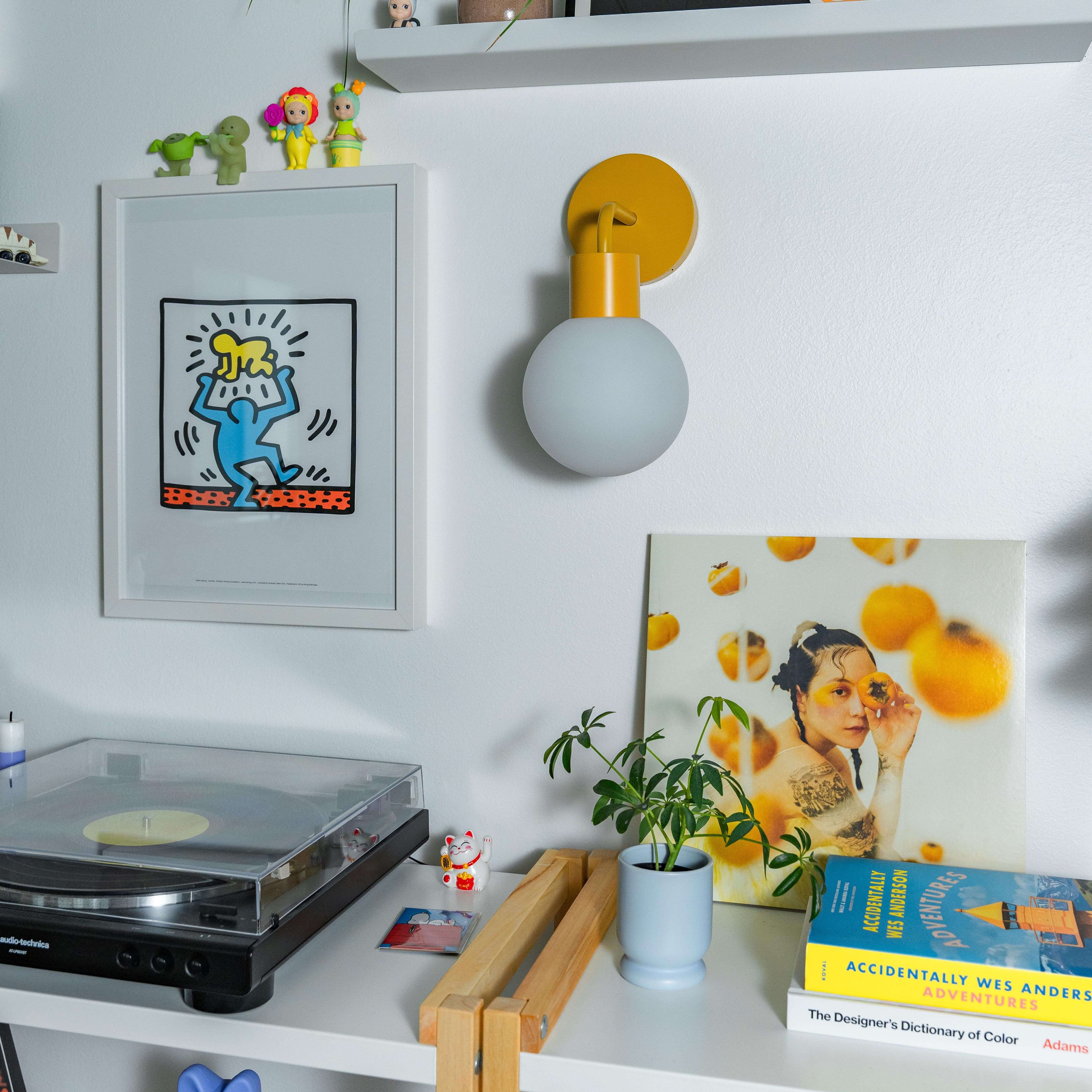 Renter-friendly rechargeable wall sconce illuminating a stylish shelf with decor and books.