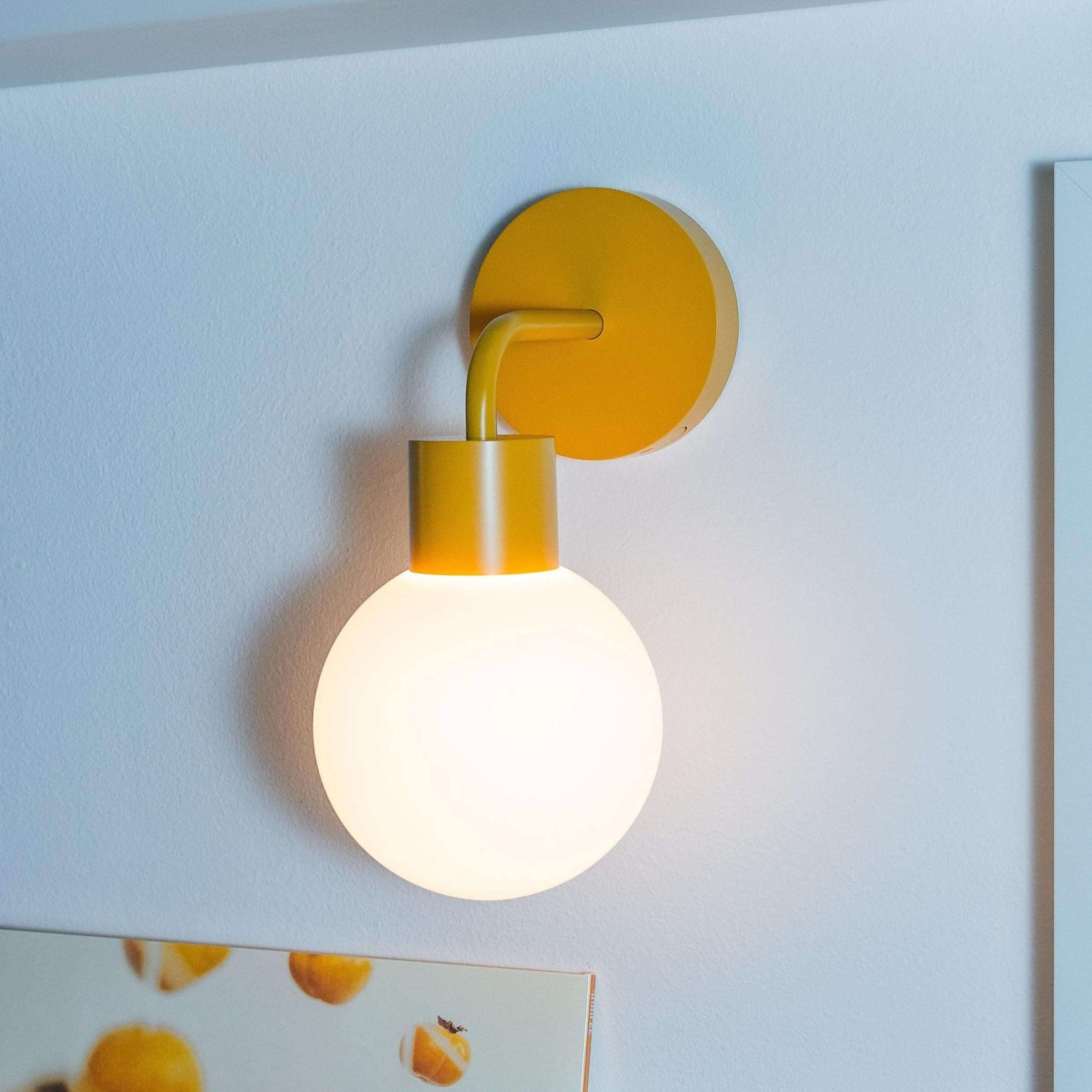 Renter-friendly rechargeable wall sconce illuminating a stylish room decor with art and plants against a white wall.