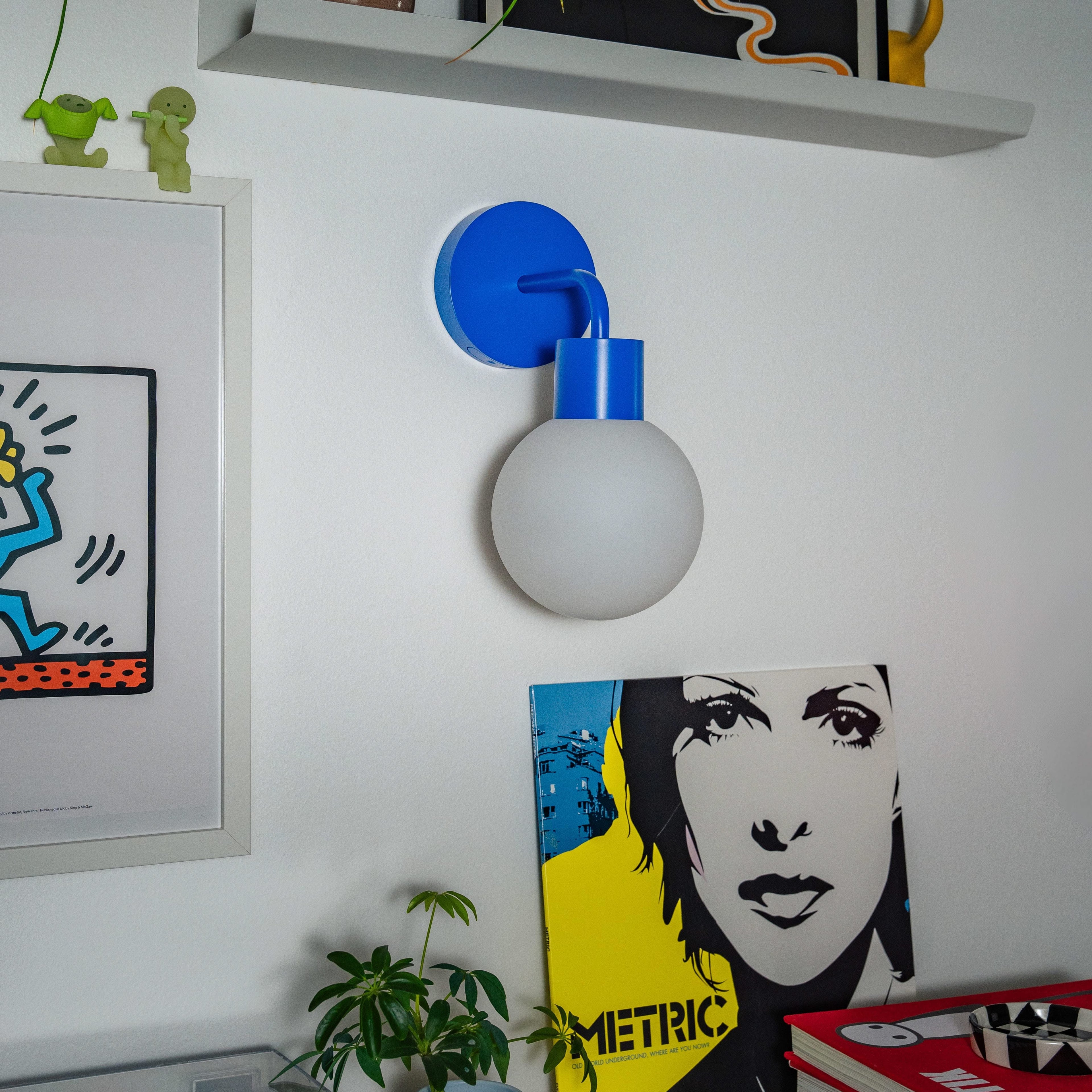 Stylish blue rechargeable wall sconce illuminating a modern room with art and vinyl records.