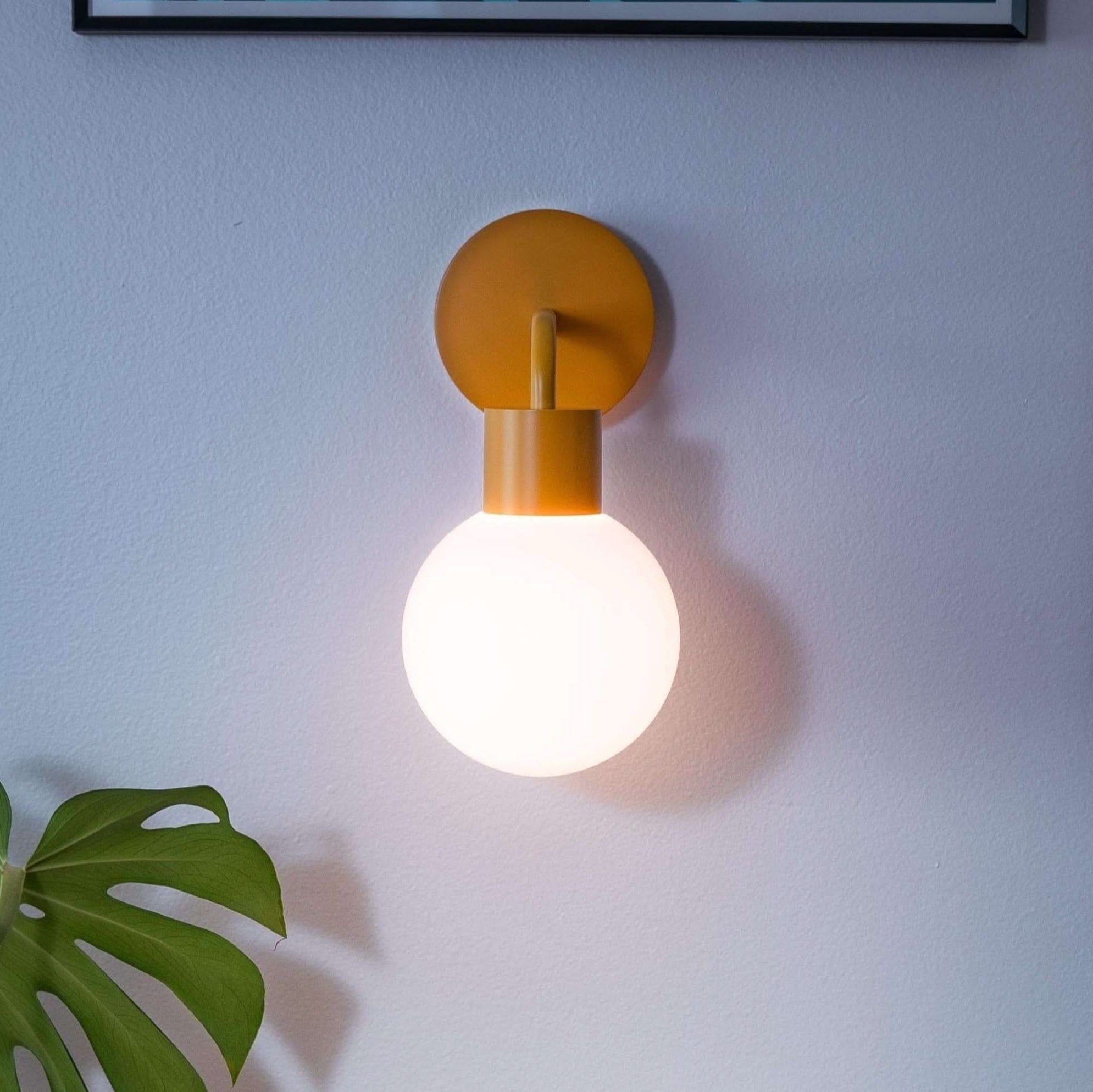 Modern renter friendly rechargeable wall sconce illuminating a cozy reading nook with books, plant, and colorful accents.