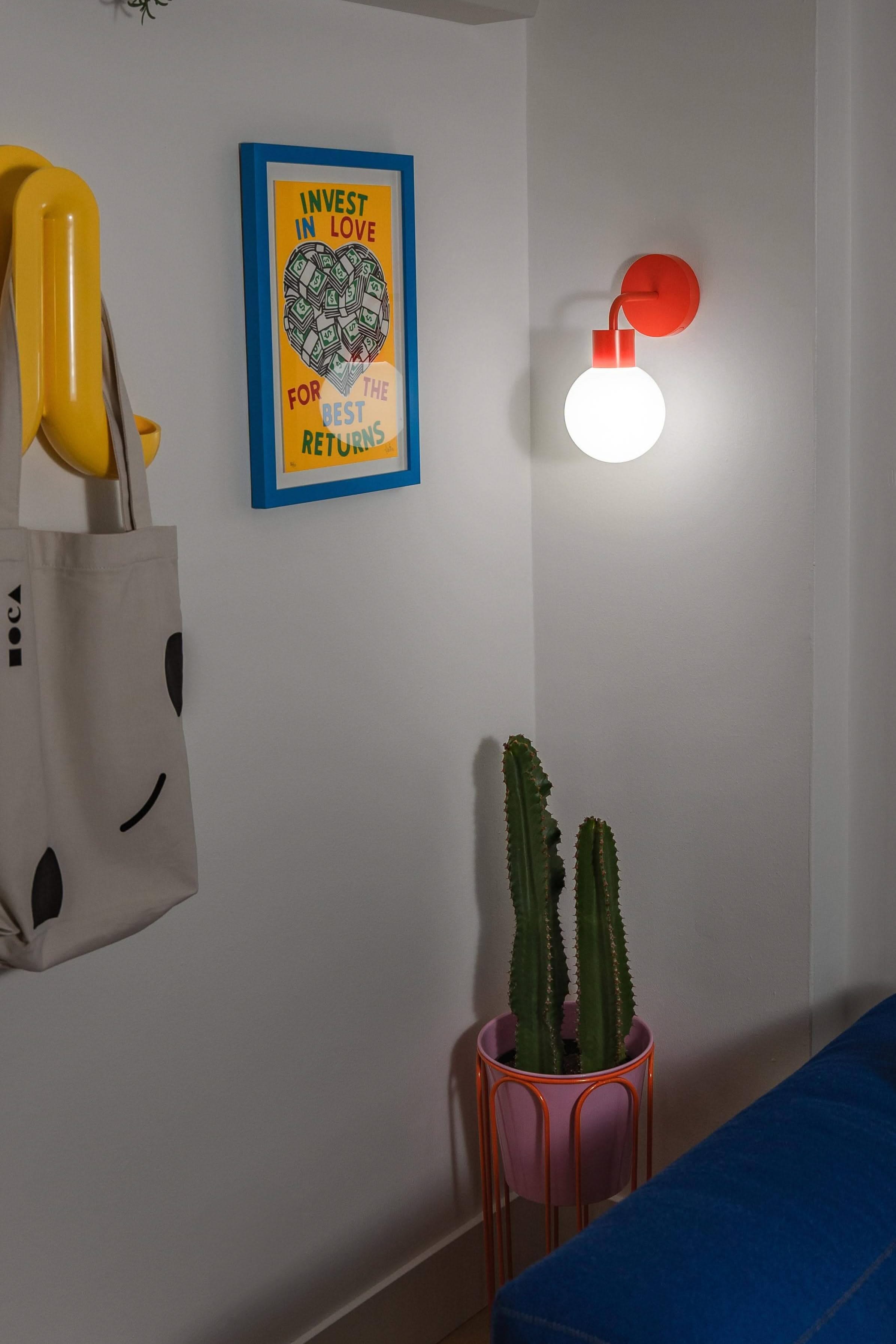 Modern renter-friendly rechargeable wall sconce illuminating a stylish living room corner with decor and cactus plant.