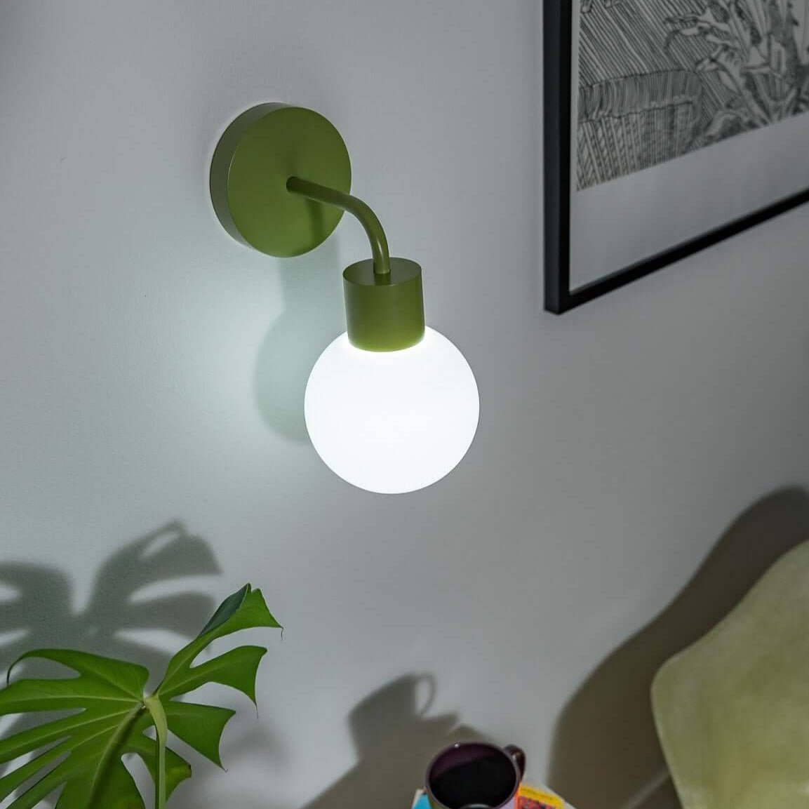 Modern stick on wall sconce illuminating a cozy reading nook with books and a plant on table