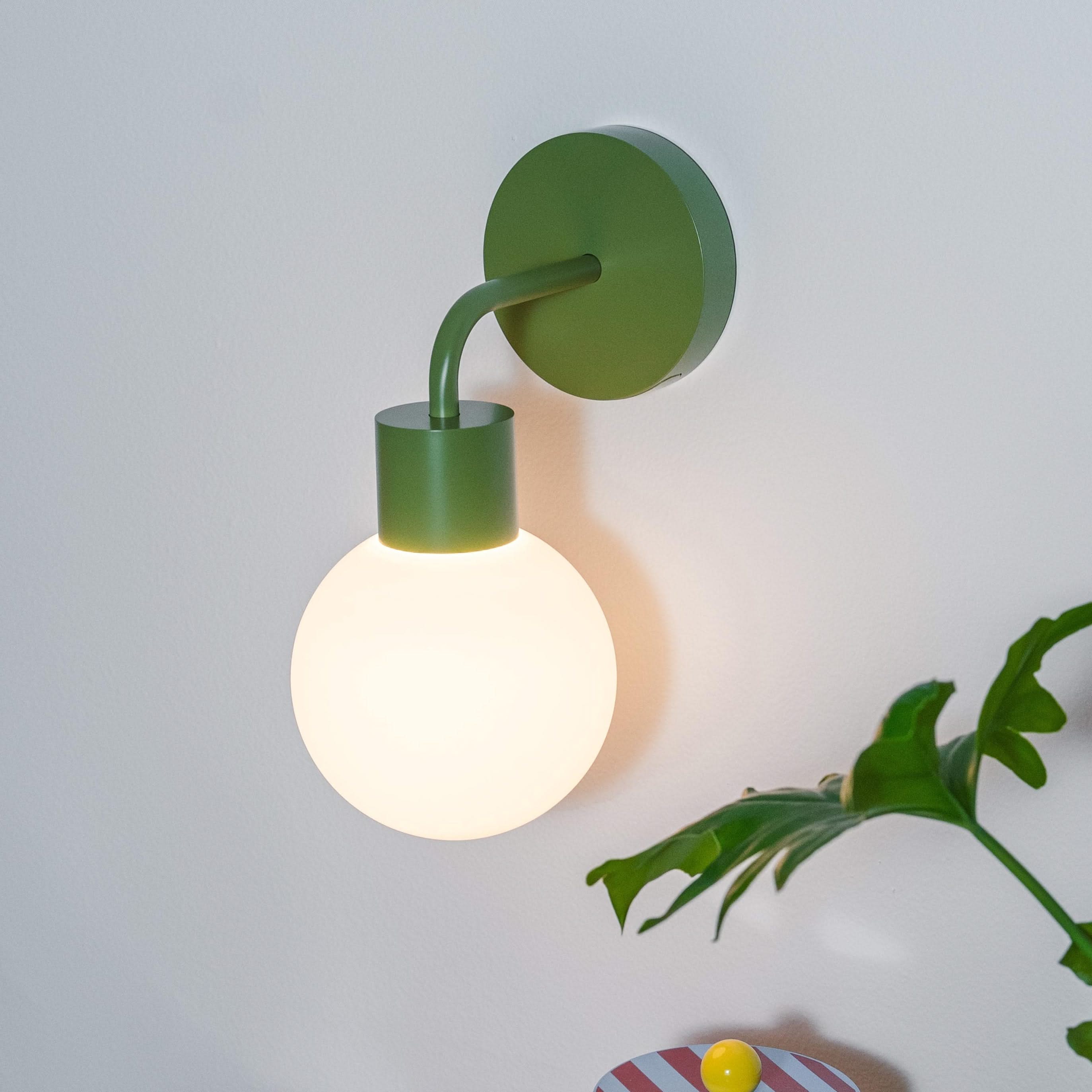 Modern rechargeable wall sconce illuminating a stylish corner with teacups, decorative items, and potted plant.