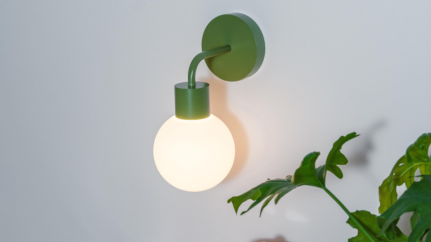 Modern rechargeable wall sconce illuminating a stylish corner with colorful decor and plants.