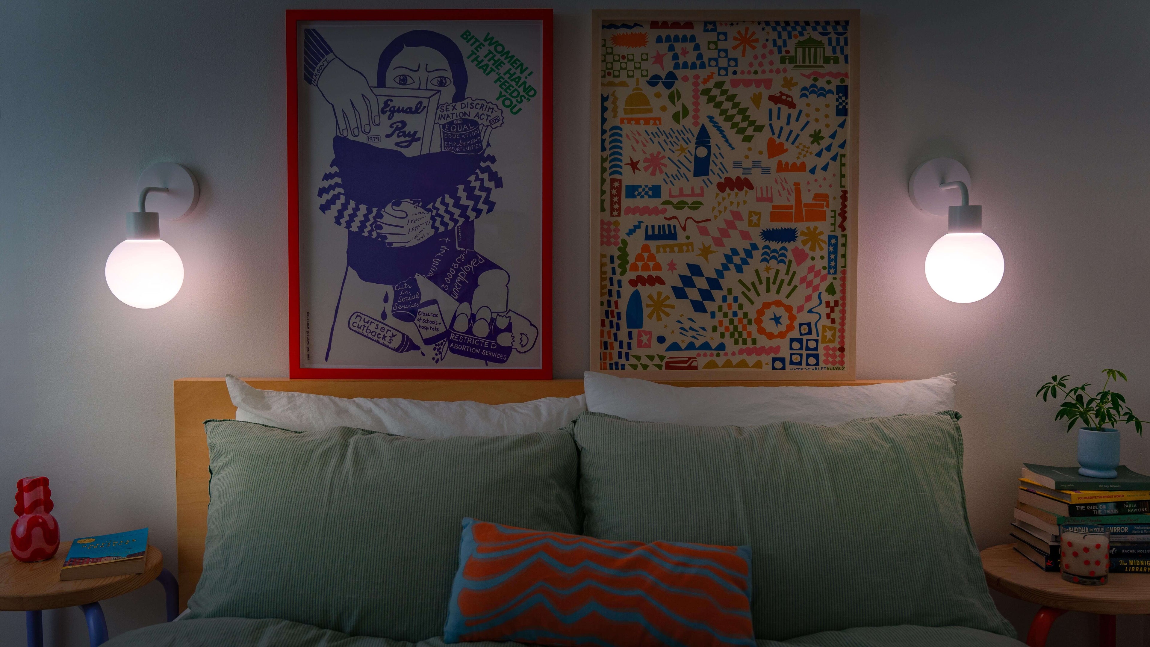 Cozy bedroom with renter-friendly rechargeable wall sconces illuminating art above a bed, creating a warm and stylish ambiance.