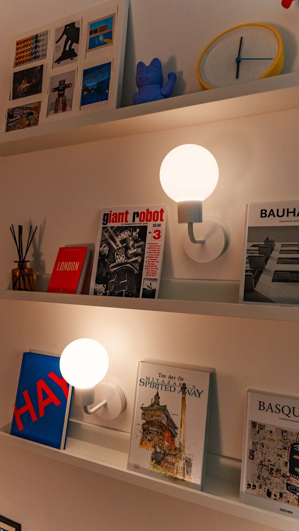 Books and decor on a modern shelf with ambient warm lighting, featuring art and architecture themes, creating a cozy, stylish space.