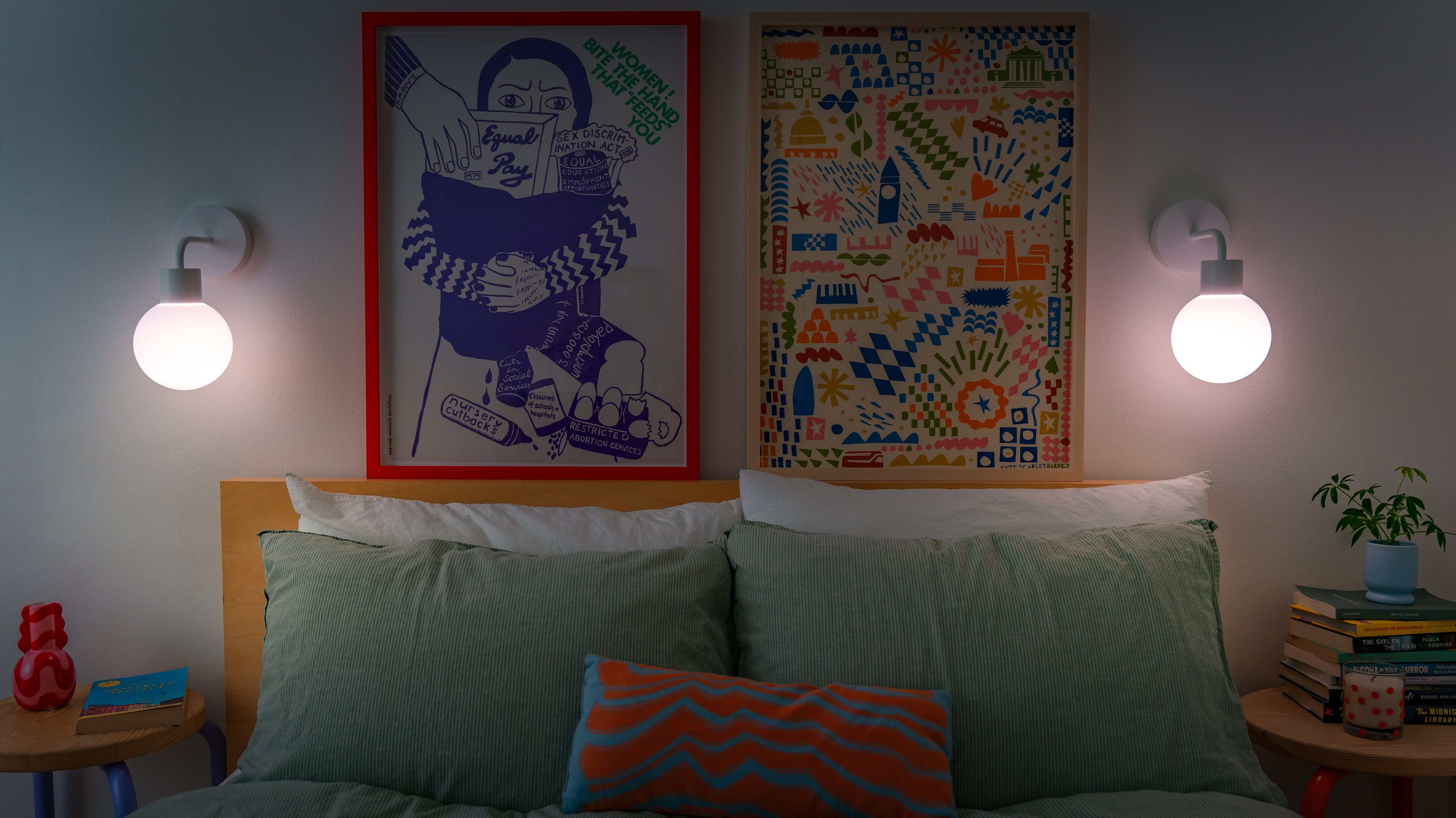 Cozy bedroom with two rechargeable wall sconces illuminating eclectic wall art and colorful bedding for a warm ambiance