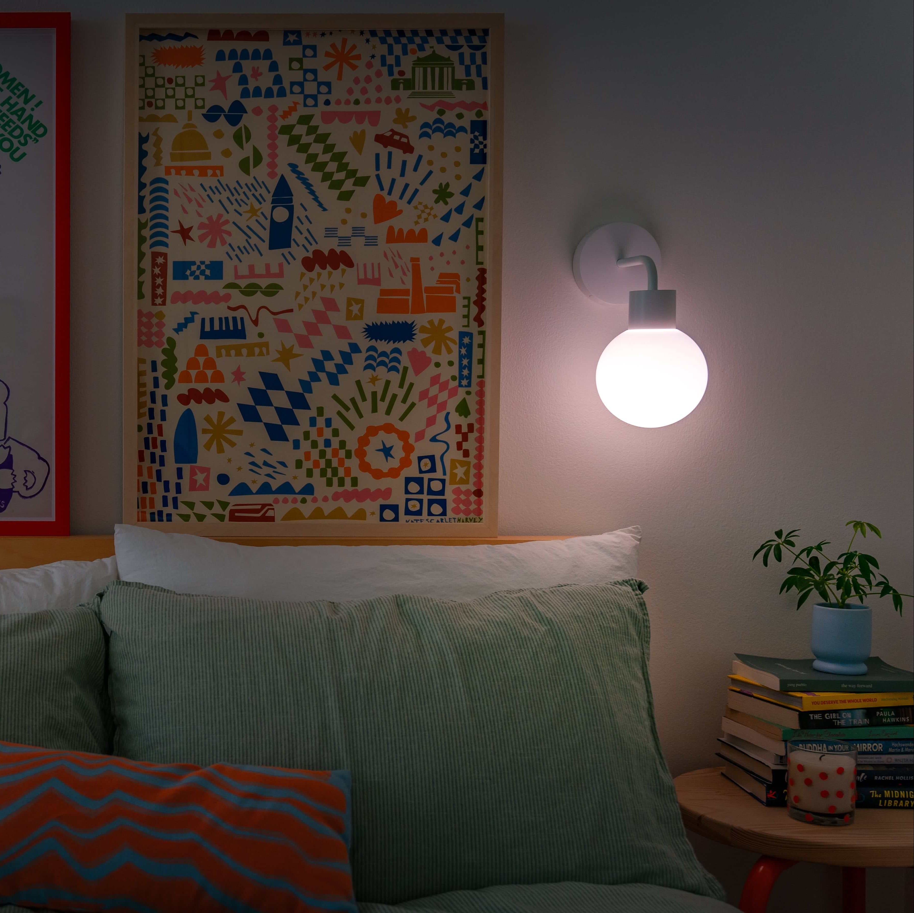 Cozy bedroom with two rechargeable wall sconces illuminating eclectic wall art and colorful bedding for a warm ambiance