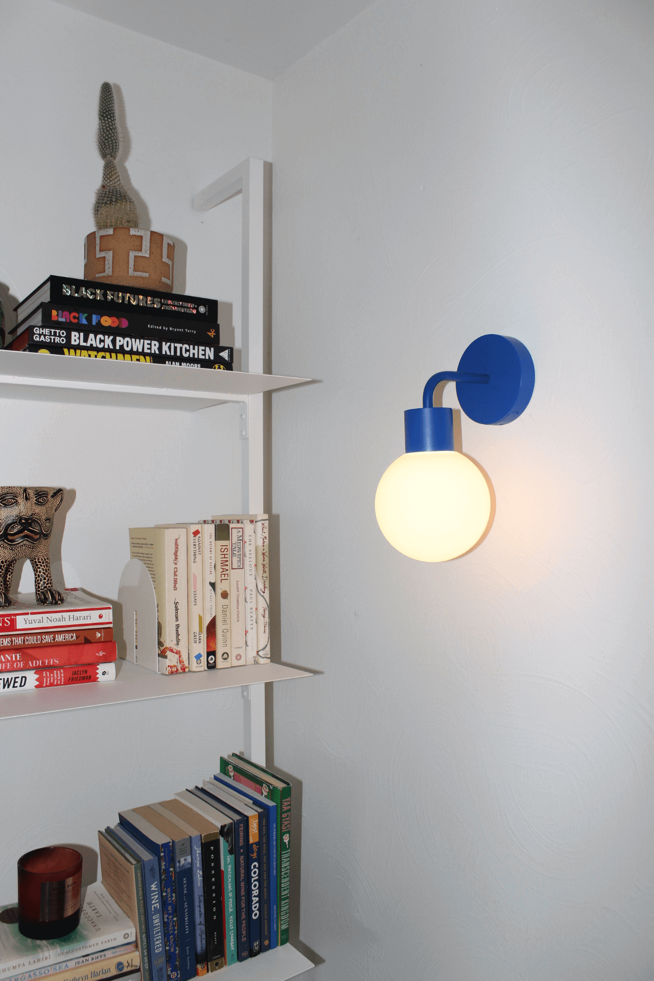 Modern blue rechargeable wall sconce illuminating a cozy reading nook, ideal for renters seeking stylish, non-invasive lighting solutions.