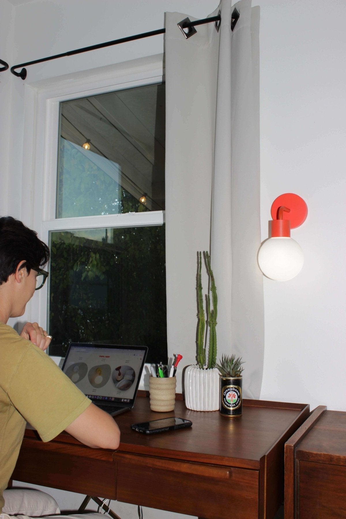 Small home office corner with vermillion red rechargeable wall sconce