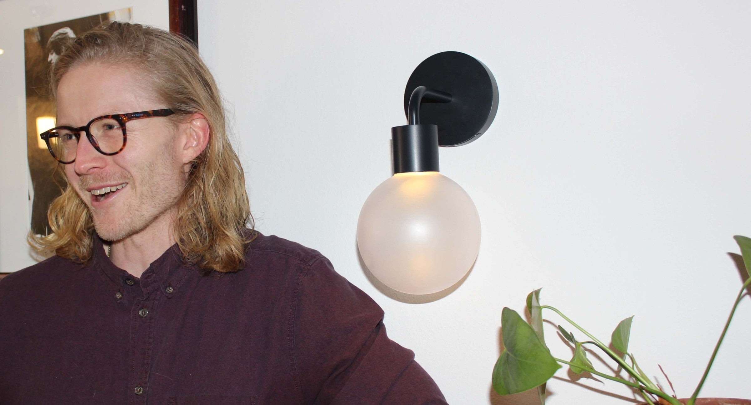 Matte black rechargeable wall light sconce and a man with eyeglass and smiling.