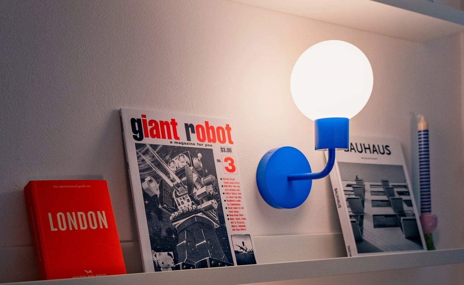 Poplight blue rechargeable wall sconce provides warm light ambience to a small bookshelves