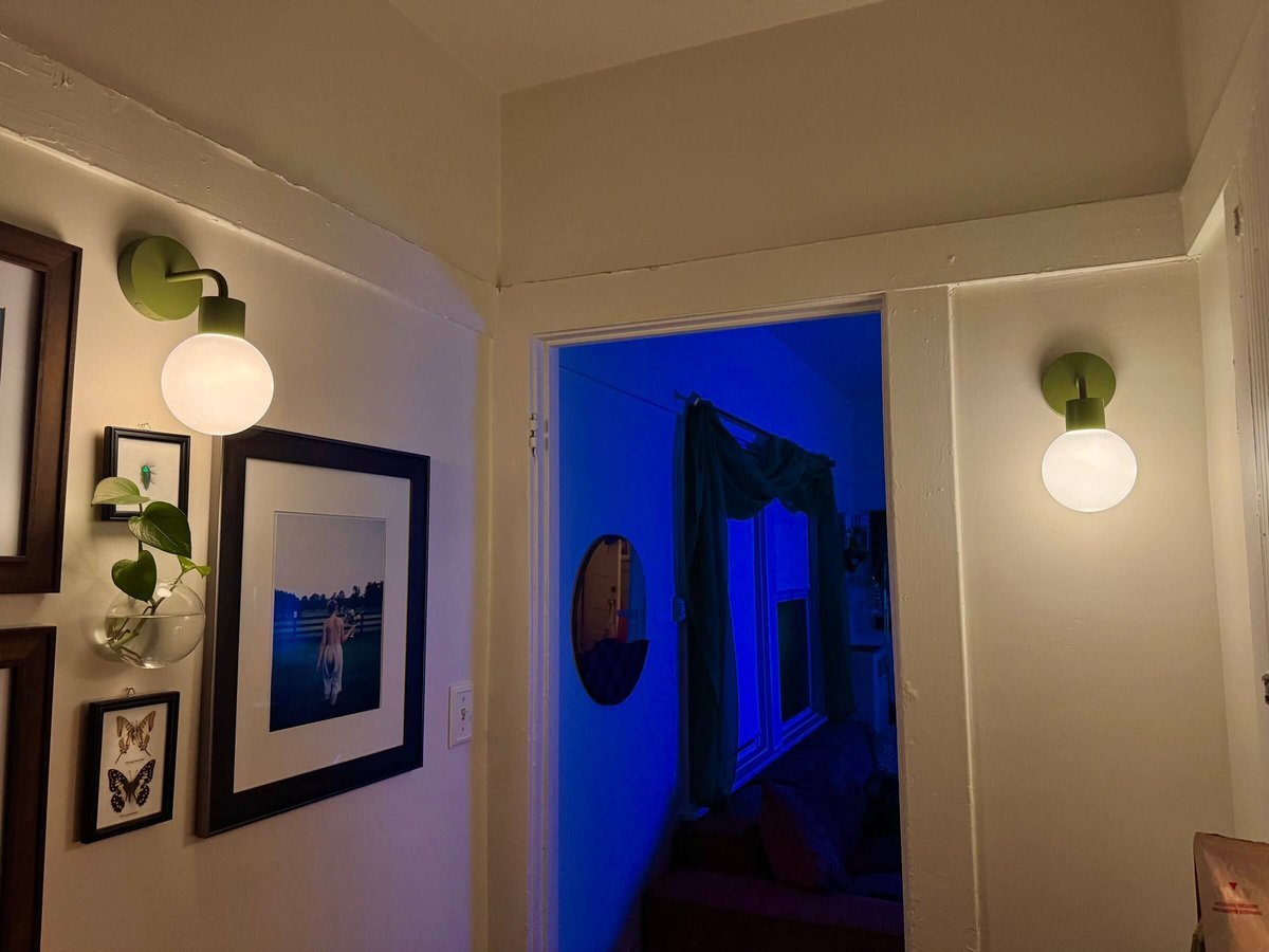 Apartment hallway warmly illuminated with Poplight sage green rechargeable wall sconces