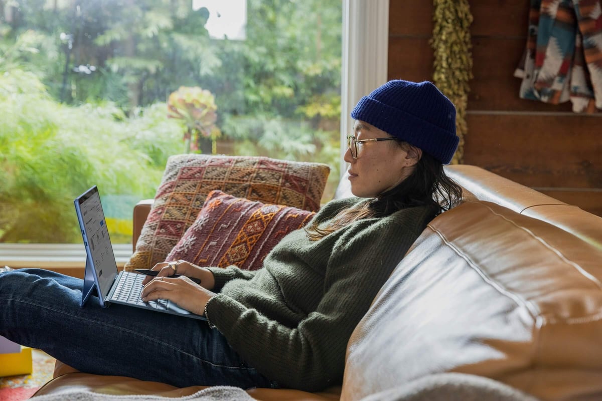A woman comfortably sitting on a couch while working.