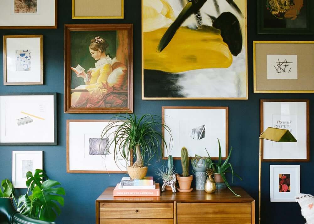 Gallery wall different pieces of artworks with small side table.