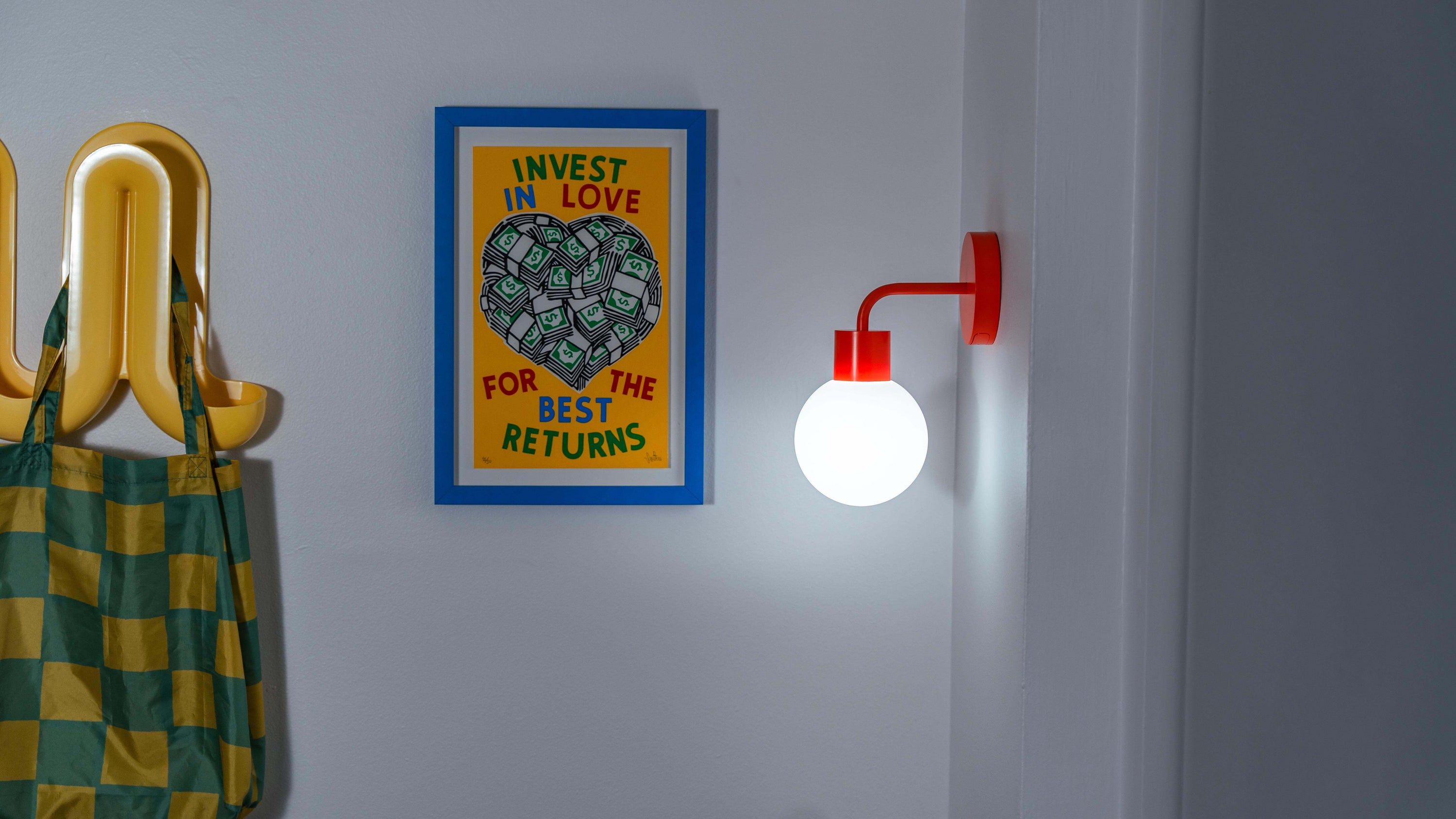Poplight vermillion red illuminating the apartment's hallway with a framed artwork and a bag hook.