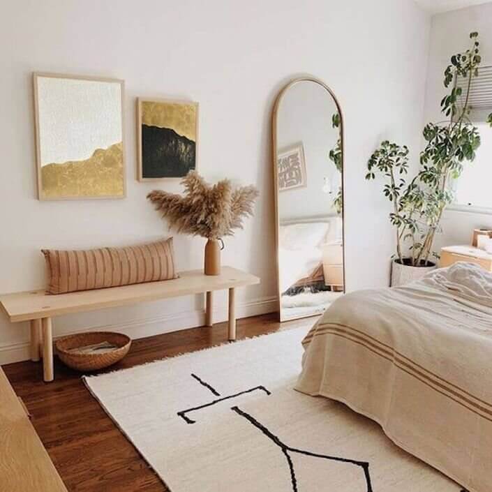 Apartment bedroom with a mirror, wall art frame, artificial indoor plant and an indoor bench chair