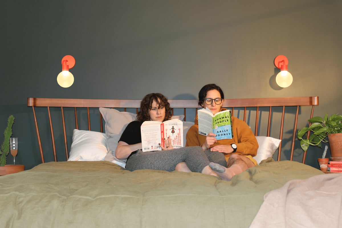 Poplight CEOs comfortably reading inside their bedroom with Poplight vermillion red as their overhead ligts