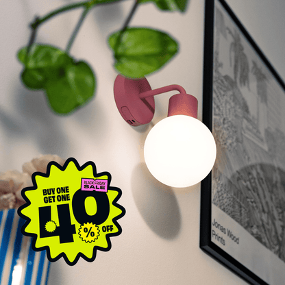 Dusty Rose Poplight rechargeable sconce positioned beside a black and white frame with promotional badge &