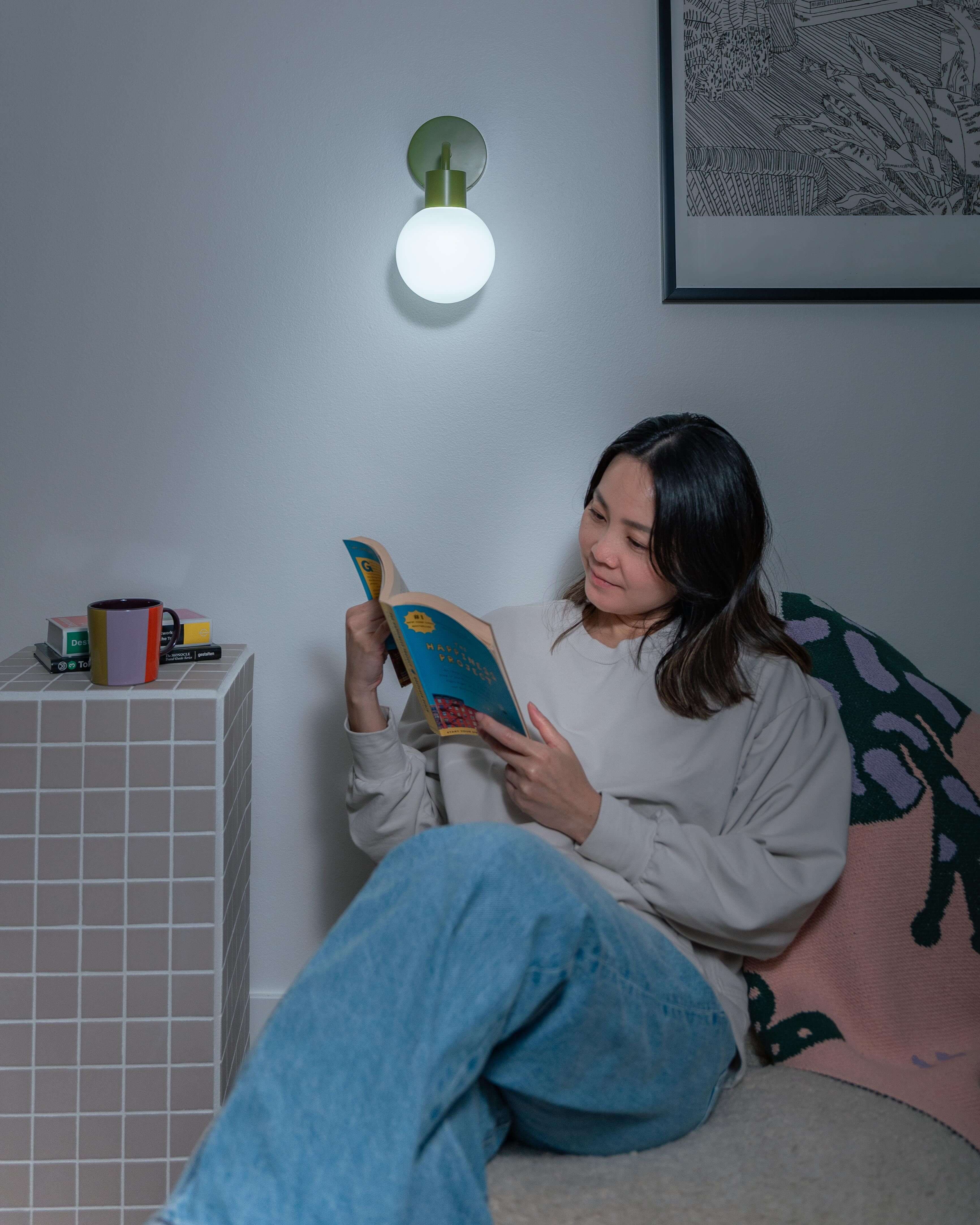 Woman reading under a renter-friendly rechargeable wall sconce, illuminating a cozy corner with modern decor.