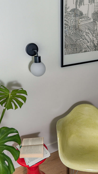 Stylish rechargeable wall sconce illuminating a modern living space with sleek decor and plants.