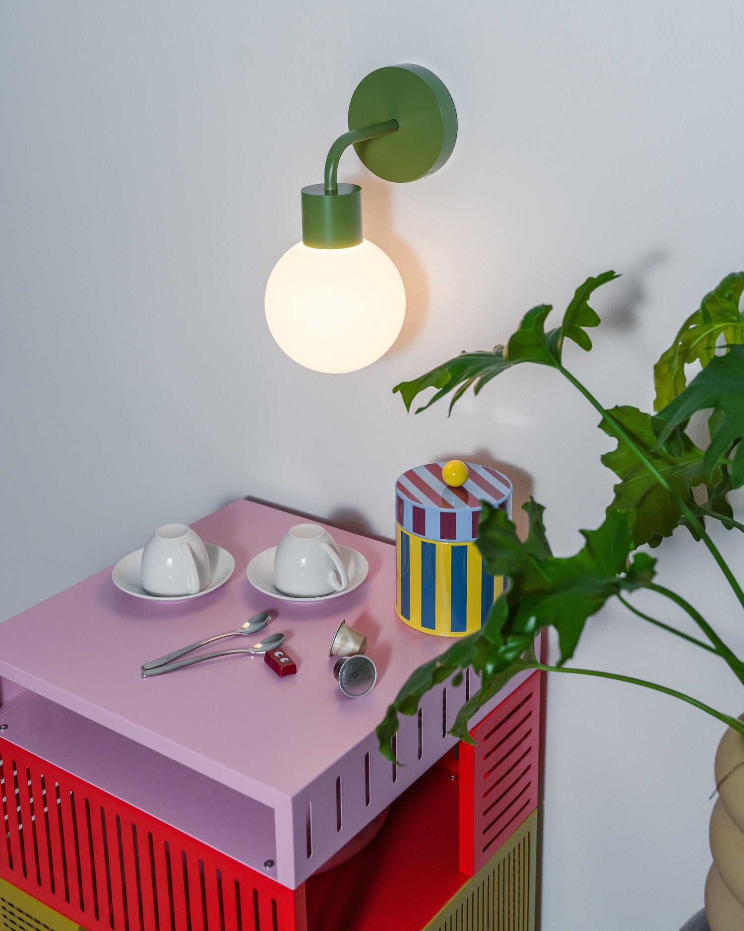 Modern rechargeable wall sconce illuminating a stylish corner with teacups, decorative items, and potted plant.