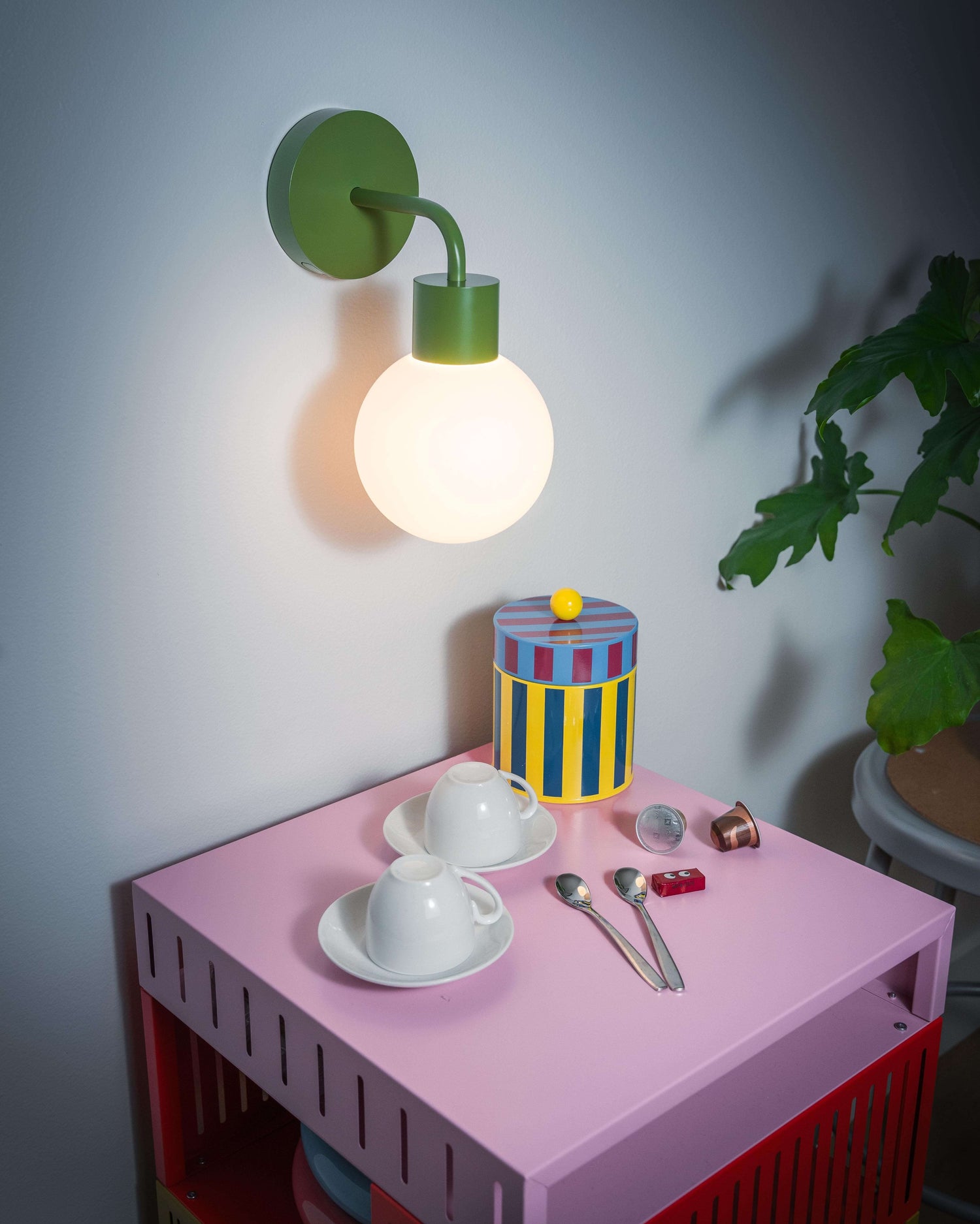 Renter friendly rechargeable wall sconce illuminating a colorful table with cups, spoons, and potted plant for stylish lighting.