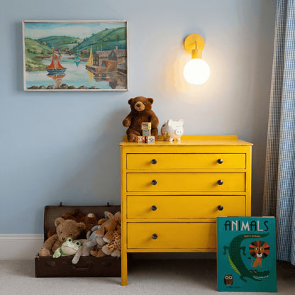 Kids playroom with yellow cabinet, animal books and a marigold wall light sconce
