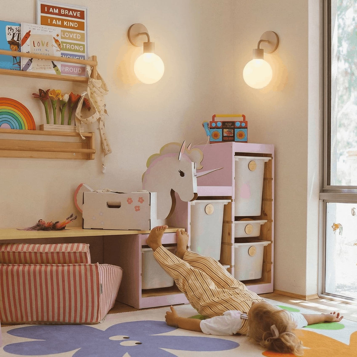 A little girl in a kids play room with two mushroom color rechargeable wall light sconces on the wall