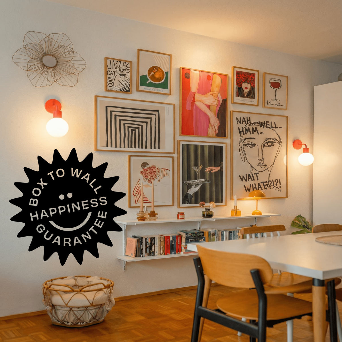 A styled interior wall with multiple framed art prints in a gallery wall arrangement, warm wall sconces, a dining table and chairs, and a large black 'Box to Wall Happiness Guarantee' badge overlaid on the lower left.