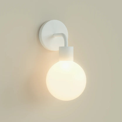 Modern wall sconce with a round glass bulb, showcasing a minimalist design and soft illumination.