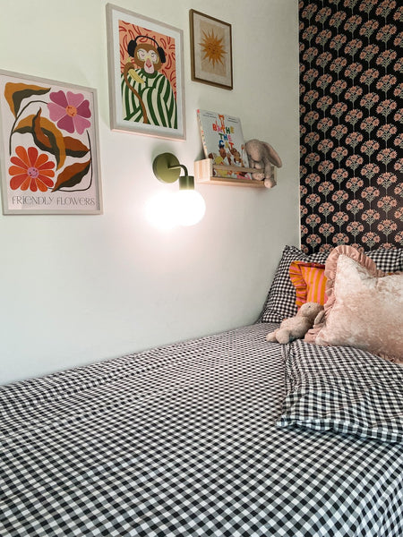 Kids bedroom with checkered bedsheet and pillow and a rechargeable wall sconce installed
