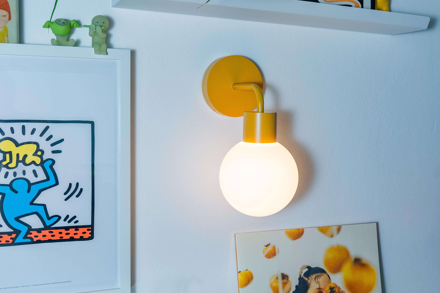 Renter-friendly rechargeable wall sconce illuminating a stylish room decor with art and plants against a white wall.