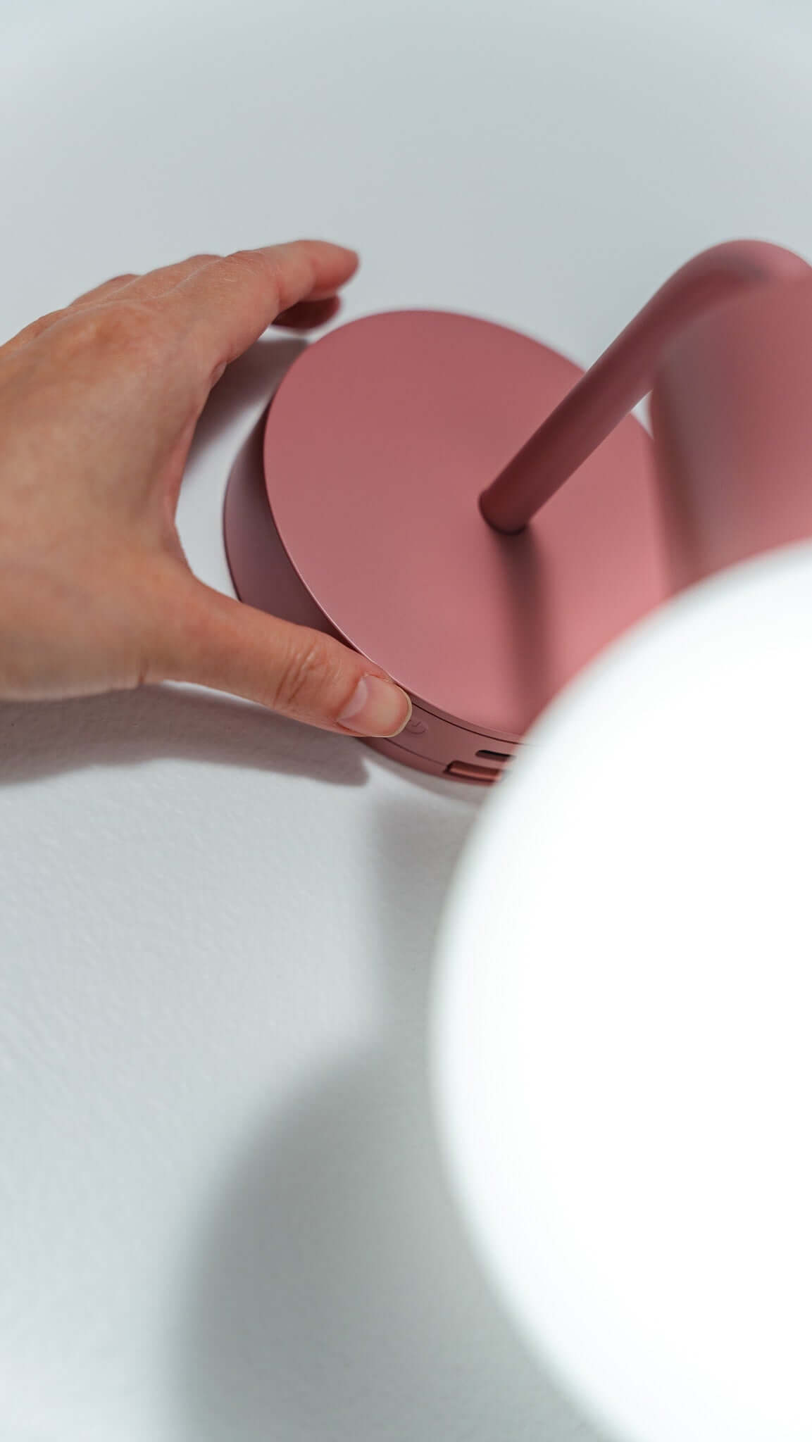 Hand adjusting modern pink wall light sconce with sleek design